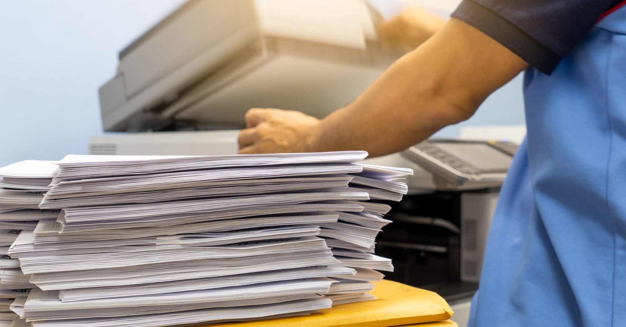 The papers stacked waiting to be scanned. Desktop scanner. In-house scanner. Document scanning.