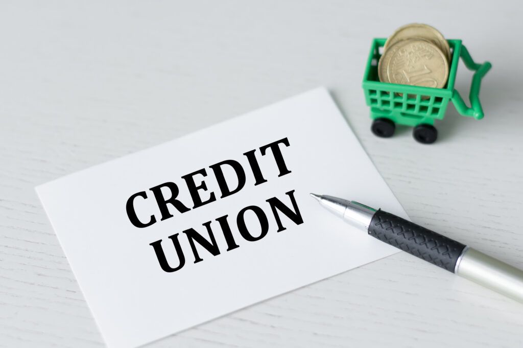 Credit Union text on a white card on the table rows pen and coins in the basket