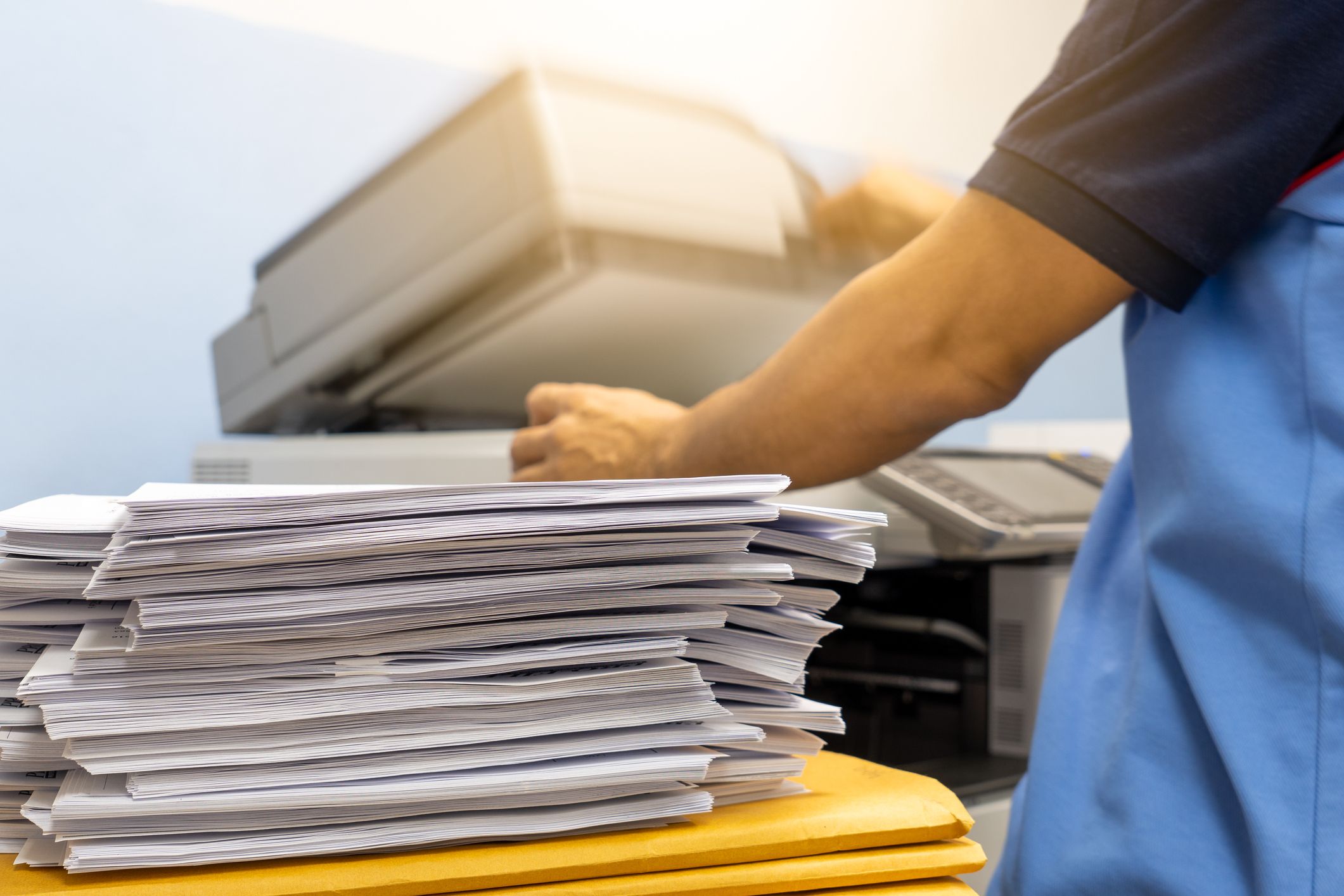 The papers stacked waiting to be copied with a copier machine.
