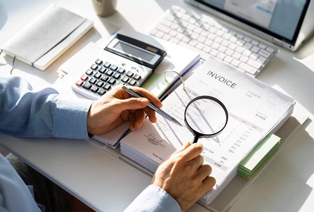 Auditor with pen and magnifying glass conducting a fraud investigation and tax audit